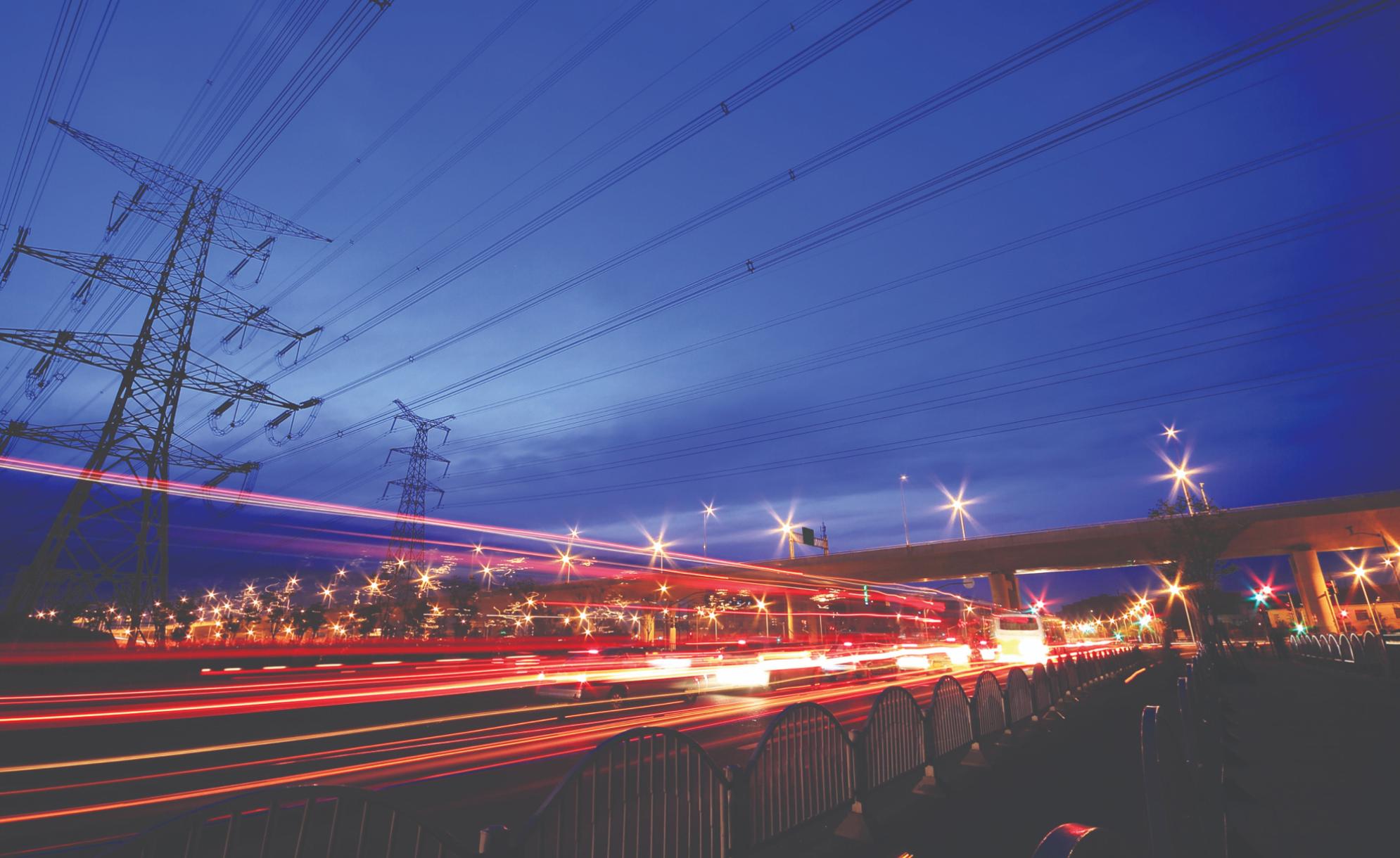 Pylons and power lines above a road at night