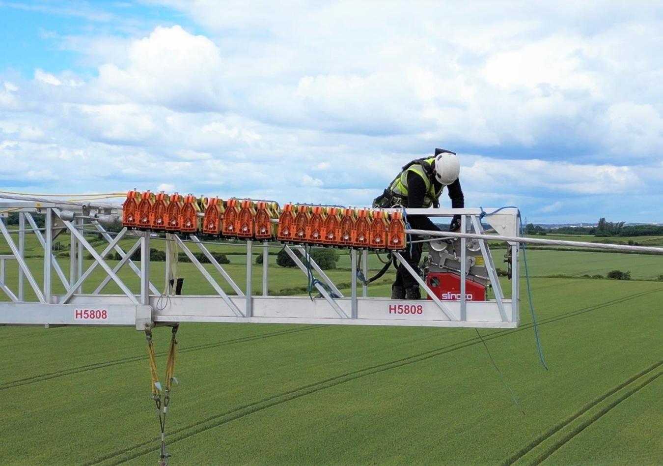 Linesman fitting conductor rollers from a suspended work platform