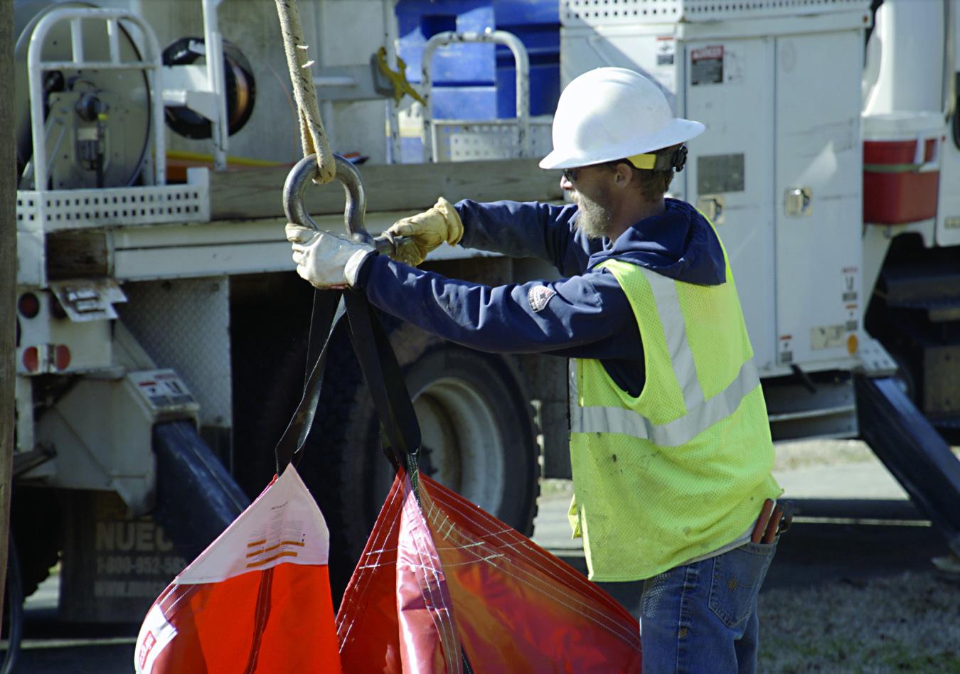 Lineworker rigging a lifting bag to a crane hook