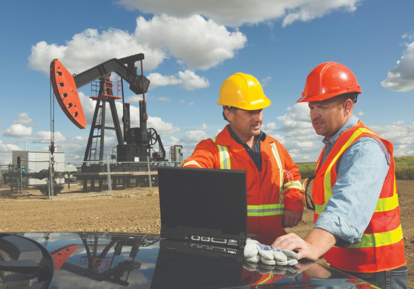 Engineers checking a laptop at an oilfield site